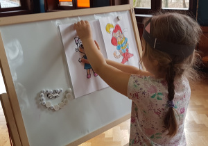 Dziewczynka przypina na tablicy ilustrację kota, po rozpoznaniu z jakiej bajki pochodzi
